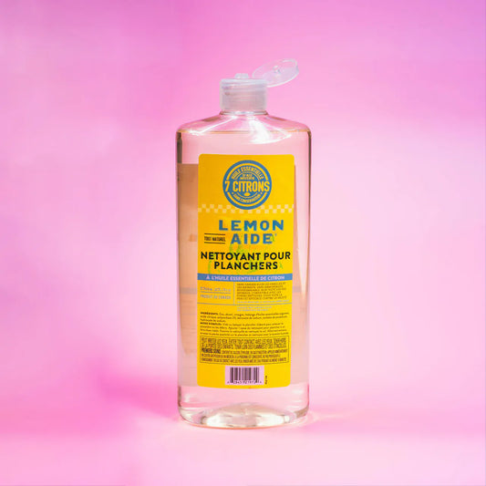 Bottle of Lemon Aid floor cleaner with a yellow label on a pink gradient background