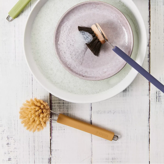 Dishwashing brushes and soapy plates on a wooden surface