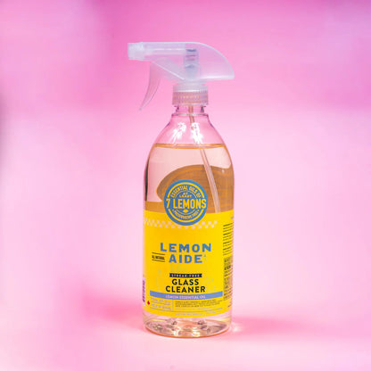 Bottle of Lemon Aide glass cleaner on a pink gradient background
